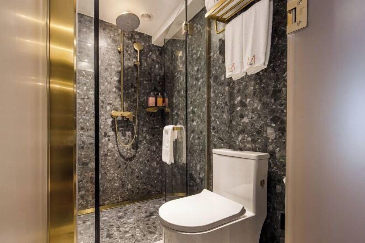 Une salle de bain moderne avec une douche à parois de verre, des toilettes blanches et des murs en marbre.