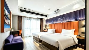 Hotelkamer met twee bedden, een bank, een bureau en uitzicht op de stad.