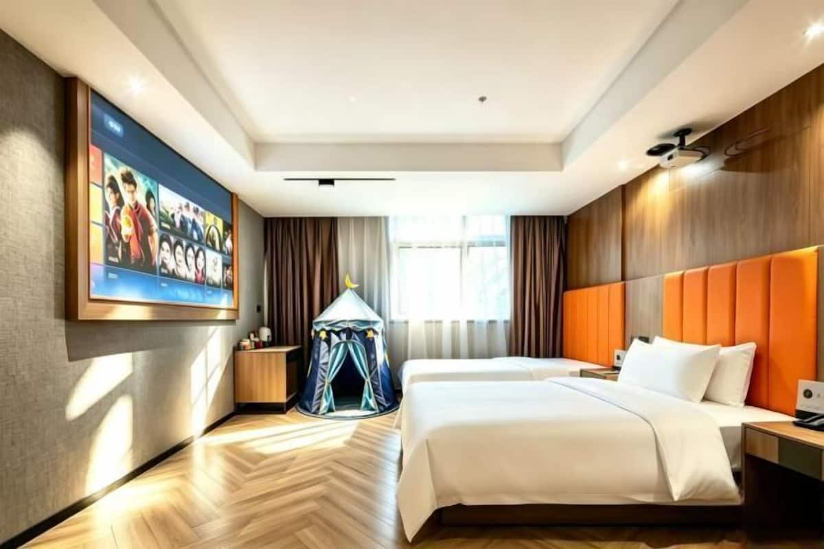 A hotel room with a large bed, a tent-like structure, a wall-mounted TV, and a window with curtains.