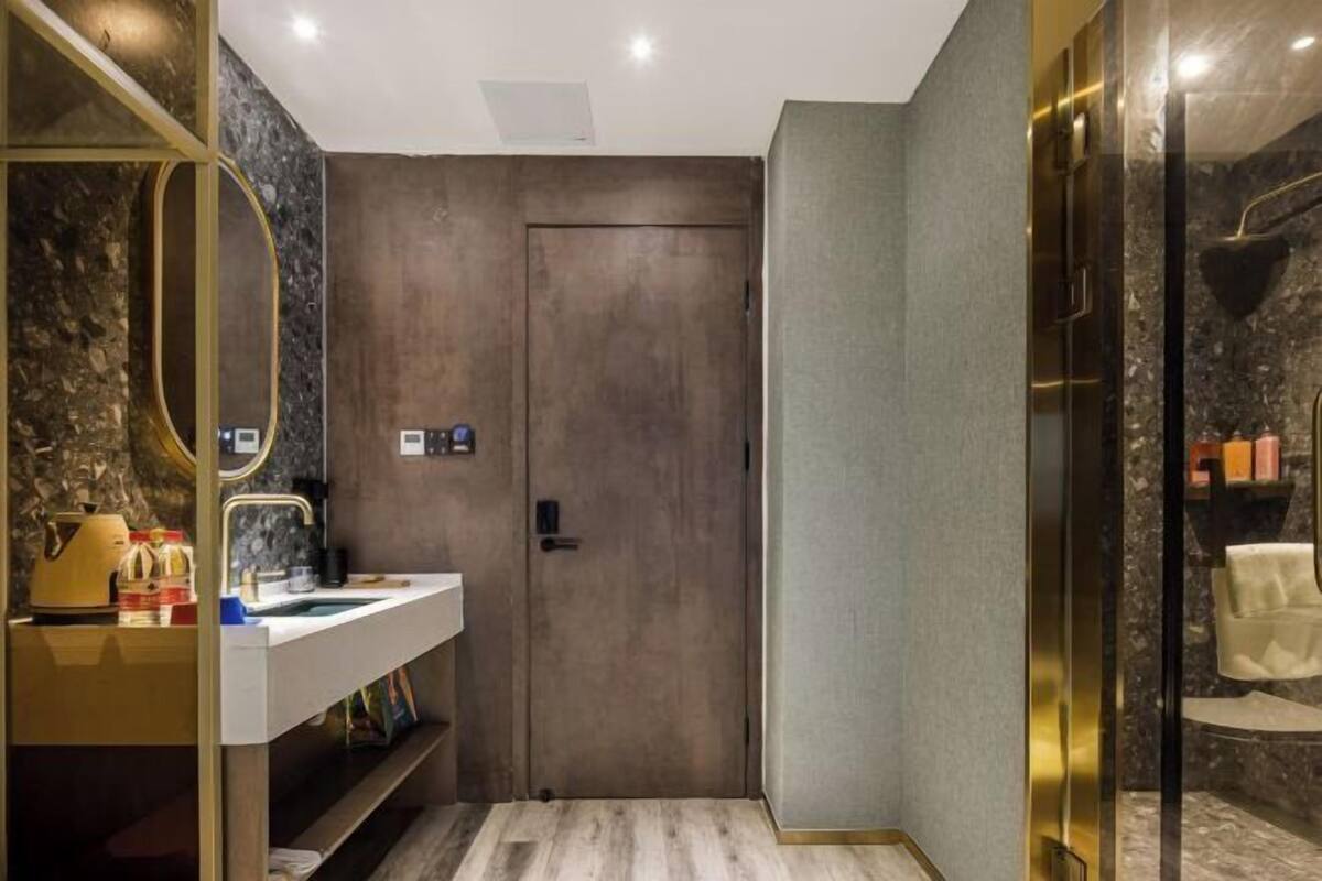 A modern bathroom with a wooden door, a white sink, and a glass shower enclosure.