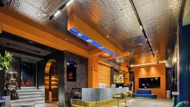 Een moderne lobby met een receptiebalie, een zithoek en een trap naar een hoger niveau.