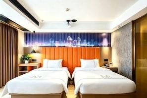 A hotel room with two beds, a cityscape mural, a modern ceiling design, and a nightstand with a lamp.
