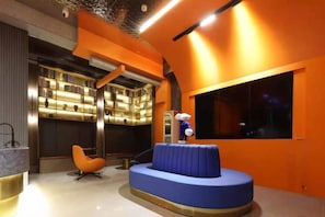 A modern interior with a blue seating area, a large window, and a wall-mounted shelf with lights. - Menory Graceful Hotel (Dinosaur Park, Changzhou Olympic Sports Center) (Changzhou)