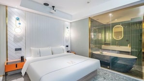 Een moderne hotelkamer met een groot bed, een douche in een glazen cabine en een minimalistisch design.
