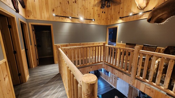 A wooden interior with a staircase, wooden railings, and mounted animal heads. - The Pull Down House! Brand New Utopia! (Jackman)