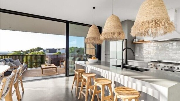 Una cocina moderna con una isla grande, taburetes de bar y vista al océano.