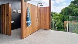 A modern bathroom with wooden paneling, a shower, and a view of greenery. - Lumiere - Stunning coastal retreat in Gnarabup (Gnarabup)