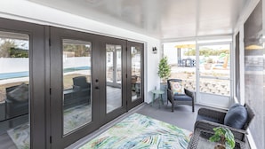 A sunlit room with a large sliding glass door leading to an outdoor patio area.