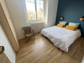 Une chambre à coucher avec un lit, une chaise, une fenêtre et un radiateur.