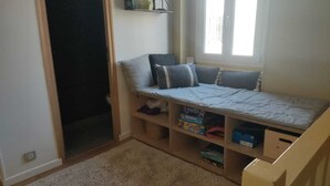 A child's bedroom with a bed, storage shelves, and a window.