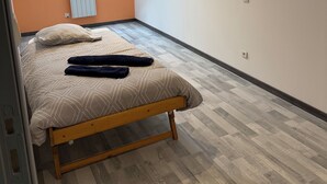 A bedroom with a sloped ceiling, a skylight, a bed with a patterned bedspread, and a radiator. - Complete stone house 130 m2 (Heuilley-le-Grand)