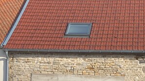 A building with a stone facade, a red-tiled roof, and a large sliding glass door. - Complete stone house 130 m2 (Heuilley-le-Grand)