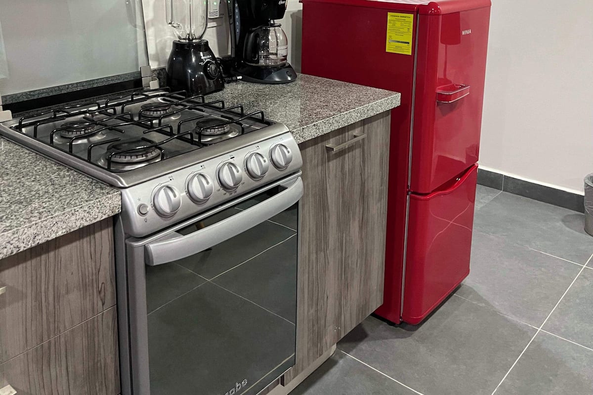 A kitchen with a gas stove, a red refrigerator, and a built-in oven.