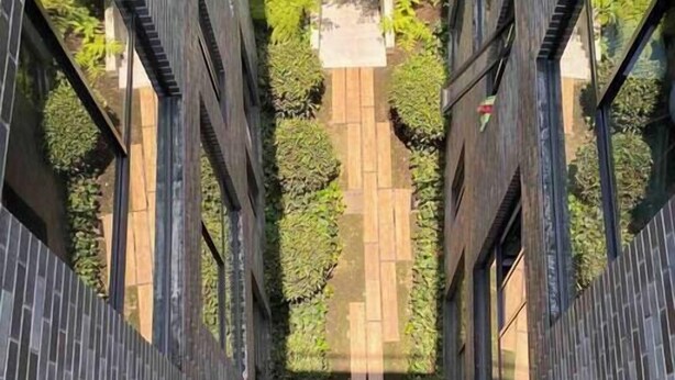 A narrow pathway flanked by dark tiled walls leading to a central area with a stone bench and greenery. - Asombroso Departamento cerca de Santa Fe (Mexico City)
