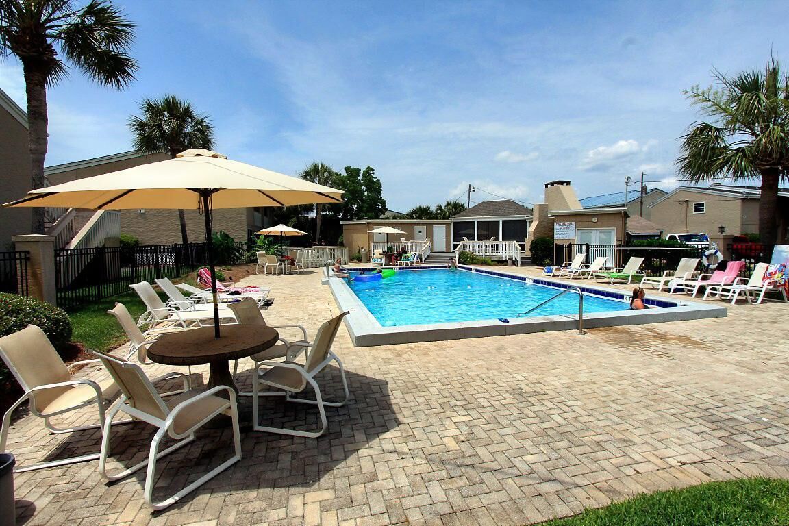 A swimming pool area with lounge chairs and umbrellas.