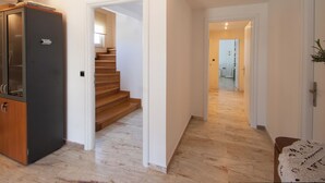 A hallway with a wooden cabinet, a staircase, and a door leading to another room. - villa penelope (Skiathos)