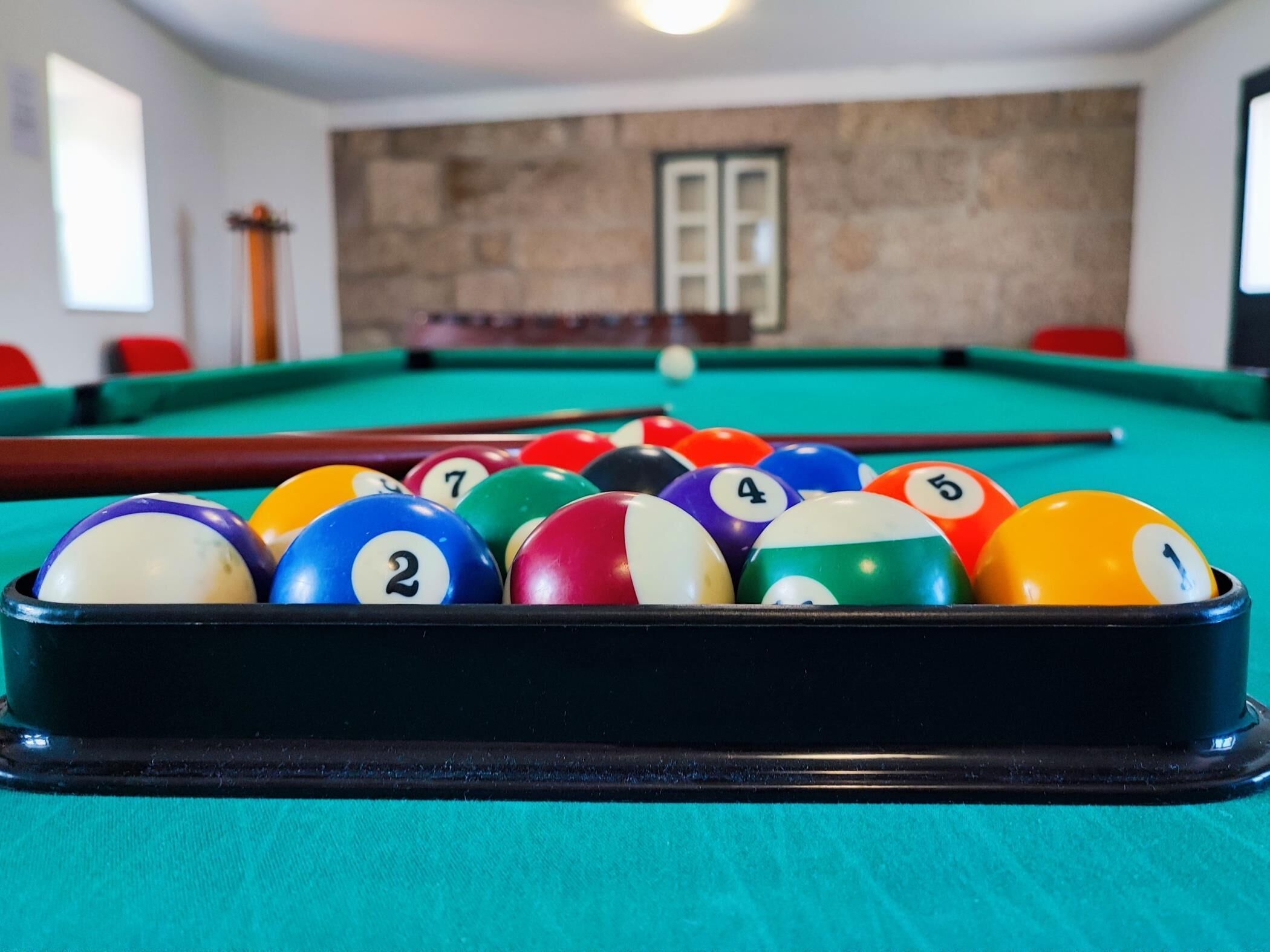 Une table de billard avec un assortiment de billes de différentes couleurs et une queue de billard bien visible.