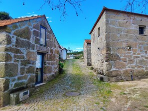 A narrow cobblestone street flanked by stone buildings with tiled roofs.