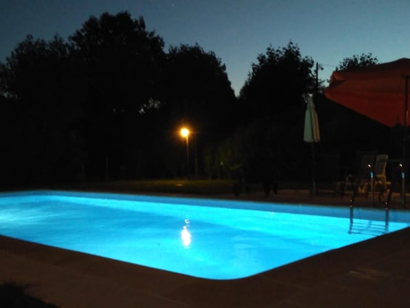 A swimming pool at night with a single light source.