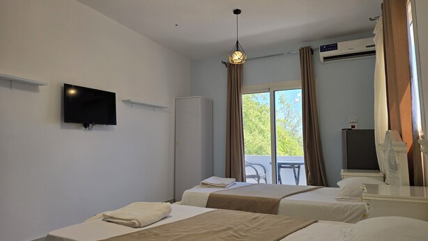 A hotel room with two beds, a TV, an air conditioning unit, and a view of the outdoors. - Manzzel Dahab Hostel (Dahab)