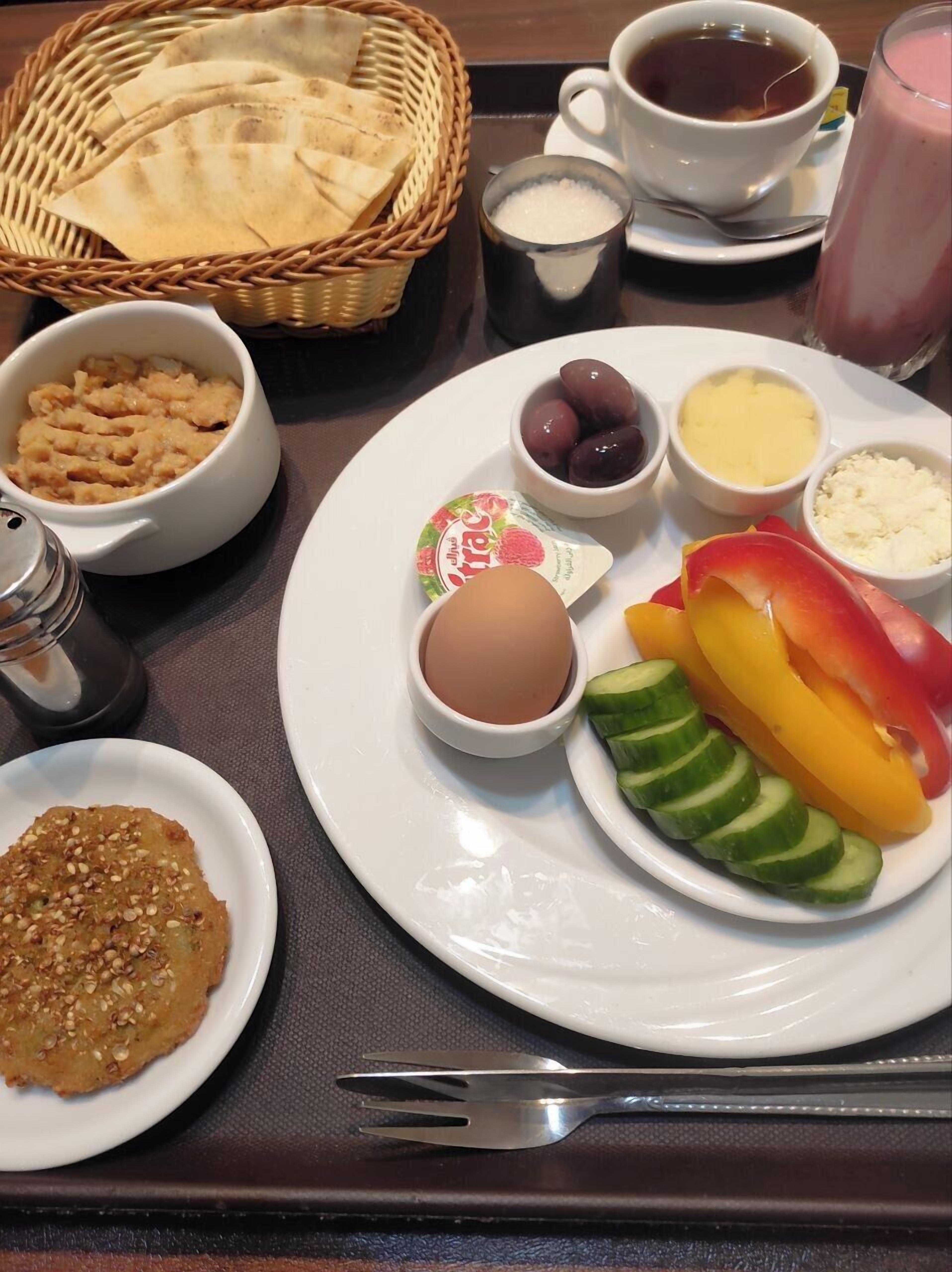 Ein Frühstückstisch mit einem Teller Essen, darunter Eier, Gemüse und eine Schüssel Joghurt.