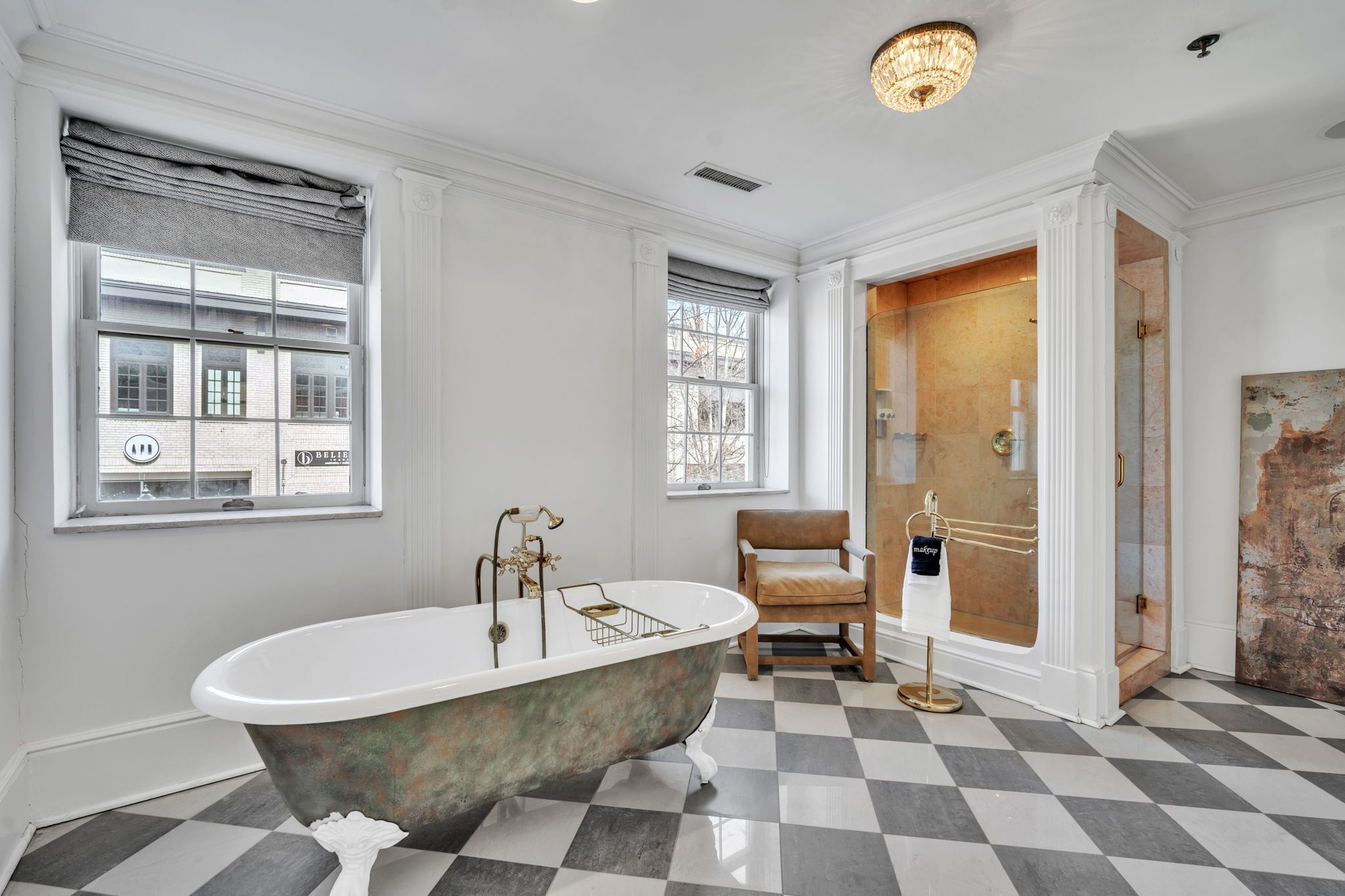 Une salle de bain avec une baignoire sur pieds, une chaise et un espace douche.