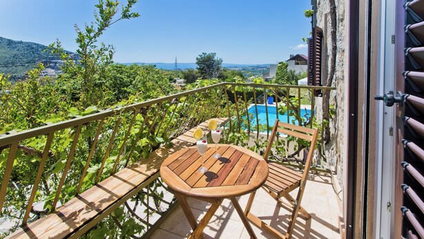 A wooden deck with a table and chairs, overlooking a swimming pool and lush greenery. - Chic 3-bedroom apartment with AC, WiFi in charming Žrnovnica (Žrnovnica)