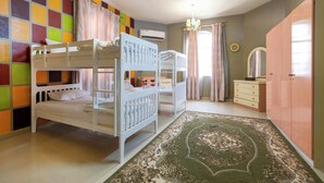 A bedroom with bunk beds, a green patterned rug, a dresser, and a mirror. - Bait Allubana Villa (Seeb)
