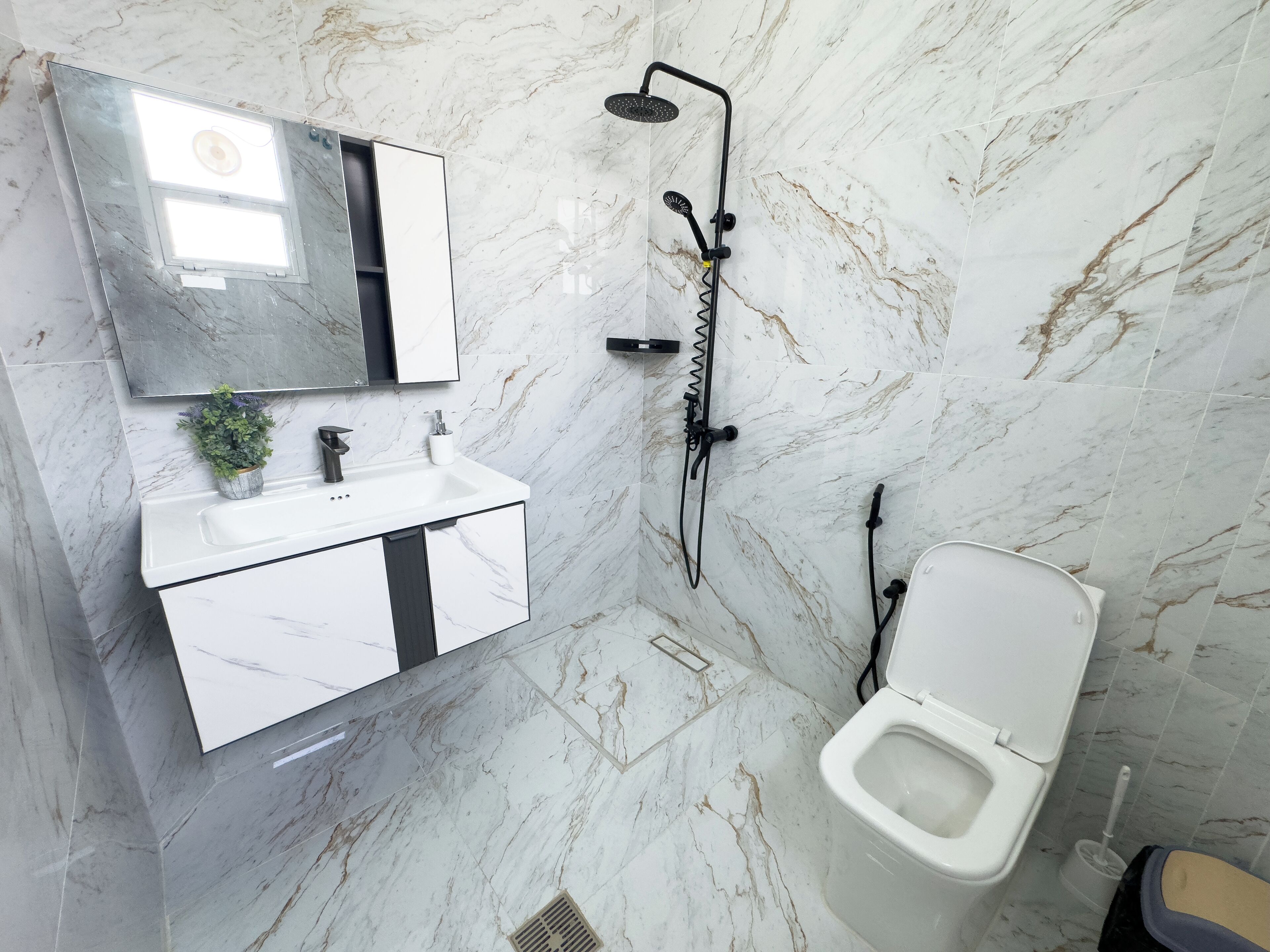 Een badkamer met een witte wastafel, spiegel en douche.