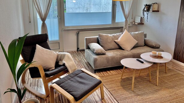 A living room with a sofa, armchair, and a small table. - Apartment near Hannibal Center (Bochum)