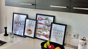 A kitchen counter with framed pictures, a candle, a glass, a fruit bowl, and a roll of paper towels. - Apartment near Hannibal Center (Bochum)