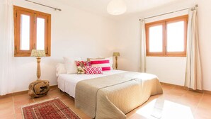 Une chambre à coucher avec un lit, deux lampes de chevet, un tapis et une fenêtre avec des rideaux.