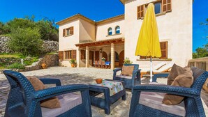 Une villa dotée d’un espace extérieur aménagé, d’une terrasse couverte et d’un mur en pierre.