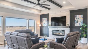 Una sala de estar moderna con chimenea, sofás de cuero y un televisor grande.