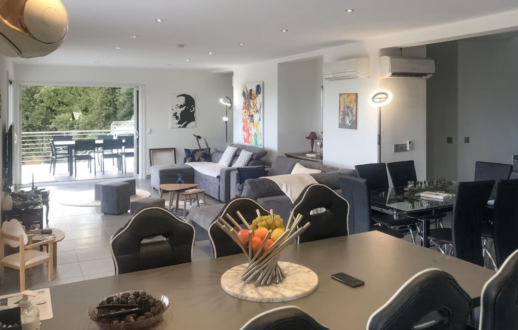 Una sala de estar moderna con comedor, que incluye un juego de sofá, una mesa de centro con fruta y una mesa de comedor con sillas.