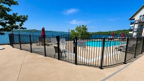 A pool area with a fence, a sign prohibiting diving, and a view of a body of water.