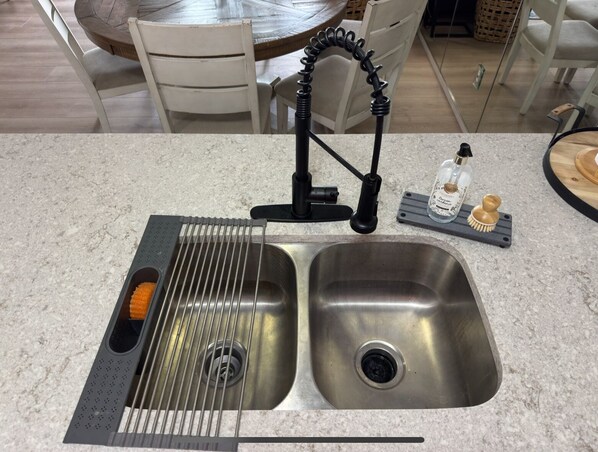 A kitchen with a double sink, a built-in grater, and a soap dispenser.