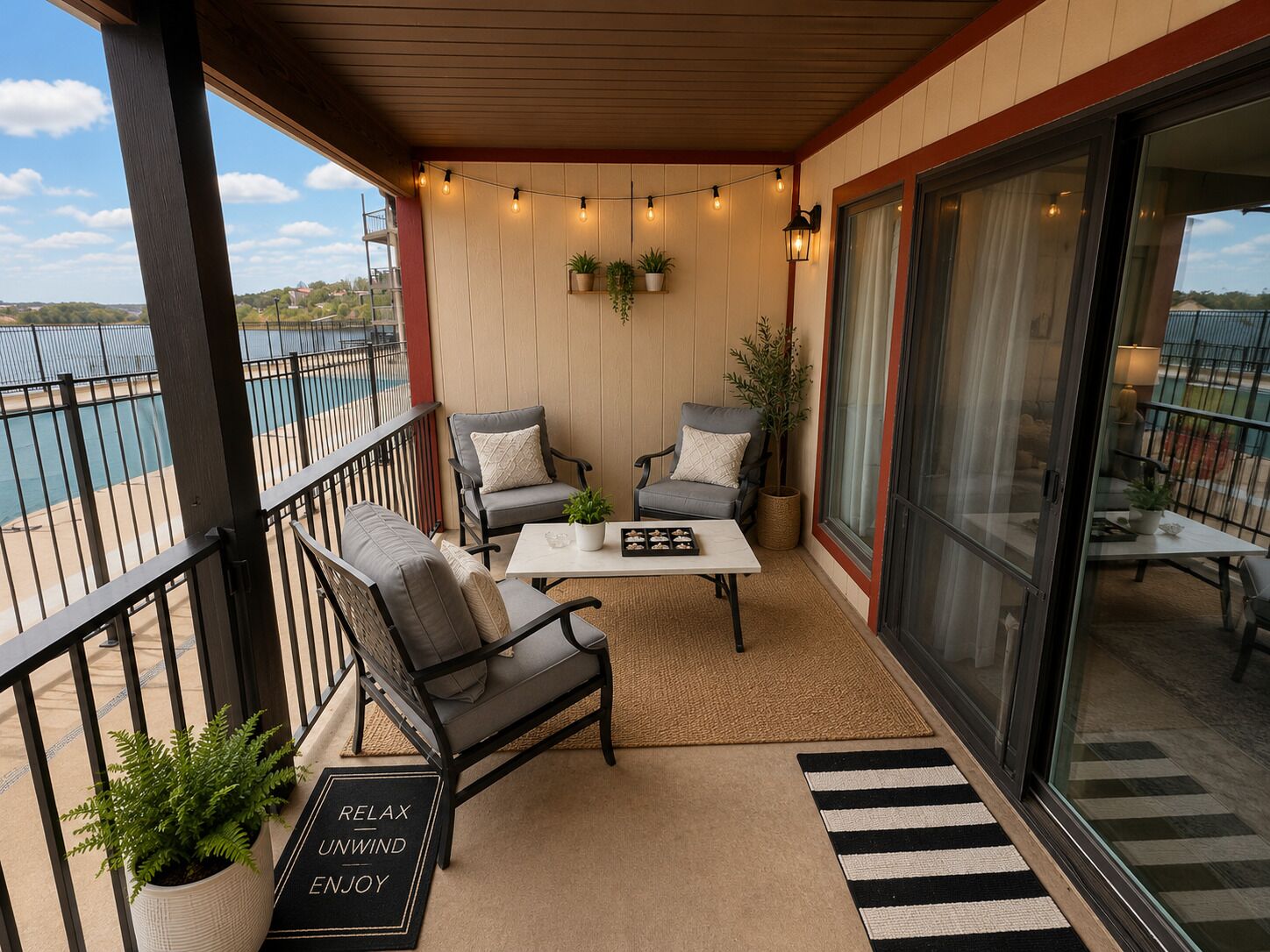A balcony with two chairs, a table, and a view of a body of water.