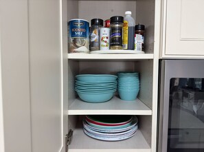 A kitchen cabinet with shelves containing various kitchen items like salt, pepper, and spices.