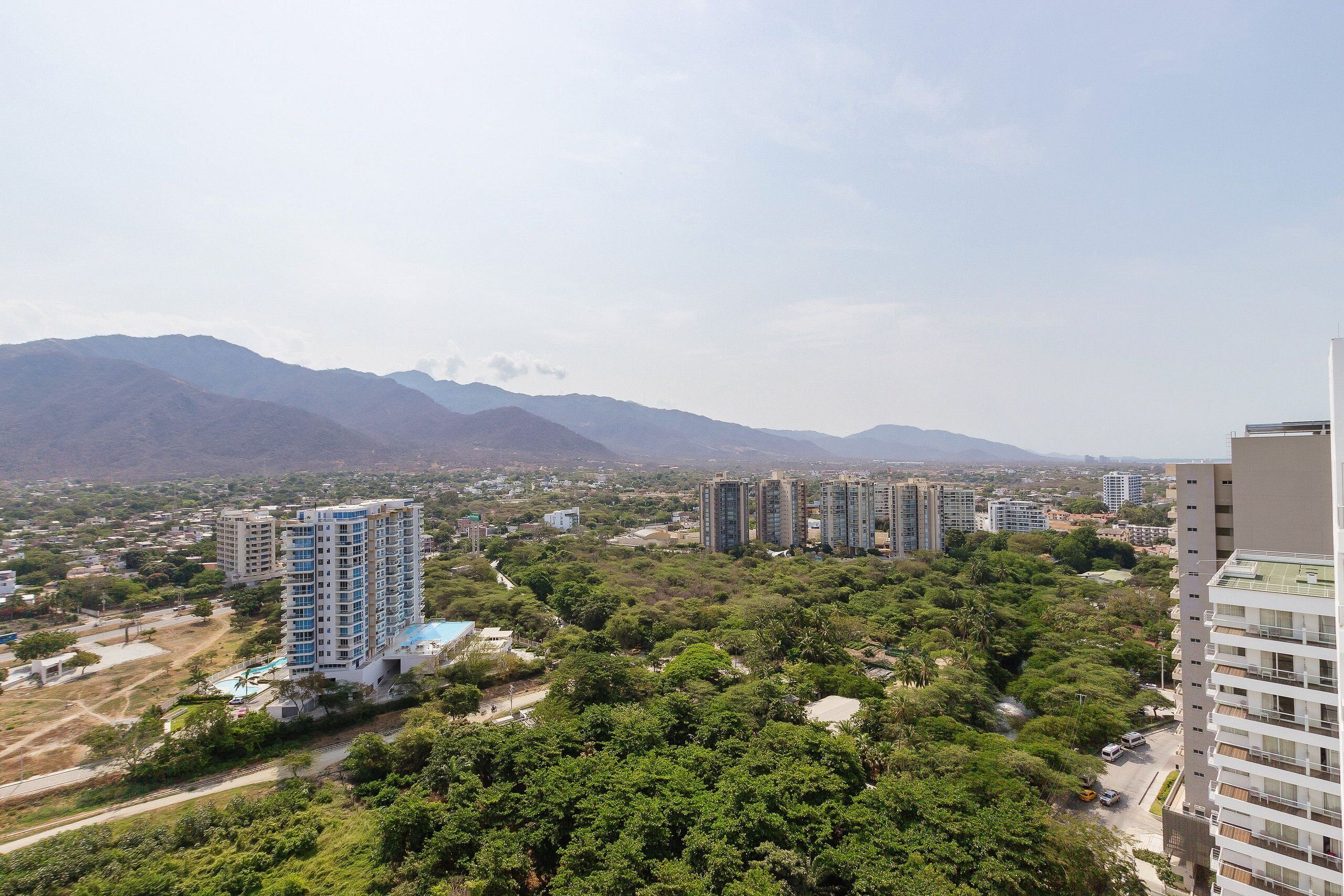 A high-rise building with multiple floors, surrounded by lush greenery and mountains in the background.