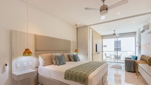 Un dormitorio moderno con una cama grande, mesitas de noche, ventilador de techo y vistas al exterior.