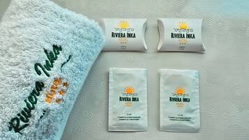 Ein weißes Handtuch mit Stickerei und drei Toilettenartikeln aus dem Riviera Inka Hotel.