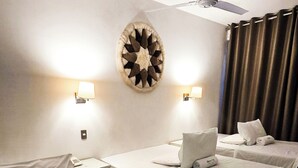 A hotel room with two beds, a ceiling fan, wall-mounted lamps, and a decorative wall piece. - Hotel en Paracas - Riviera Inka (Paracas)