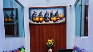 A room with two wicker sofas, a small table with a vase of flowers, and a wall-mounted artwork. - Hotel en Paracas - Riviera Inka (Paracas)