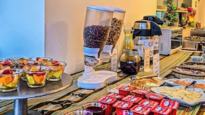 A buffet setup with various food items and drinks, a clock, and a window with a view of the outside. - Hotel en Paracas - Riviera Inka (Paracas)