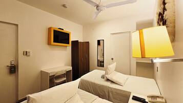 Una habitación de hotel con dos camas, un escritorio, un televisor, un espejo, una lámpara y un teléfono.