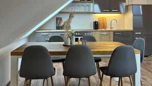 A modern kitchen with a wooden dining table and four chairs, a built-in oven, and a stainless steel refrigerator. - High Up Retreat (Linz)