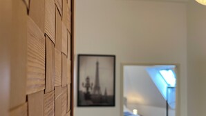 A room with a wooden wall panel, a framed picture of a tower, and a bed with a blue headboard. - High Up Retreat (Linz)