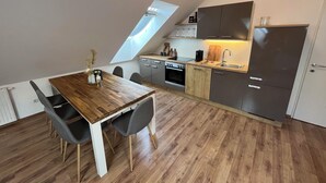 A modern kitchen with a wooden dining table, grey chairs, and a built-in oven. - High Up Retreat (Linz)
