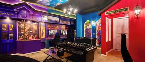 A room with a purple and red color scheme, a sofa, a table, and a sign for 'Potions & Spells'.